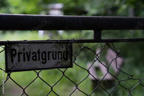 German sign on a fence saying private property - bench and grass in the background