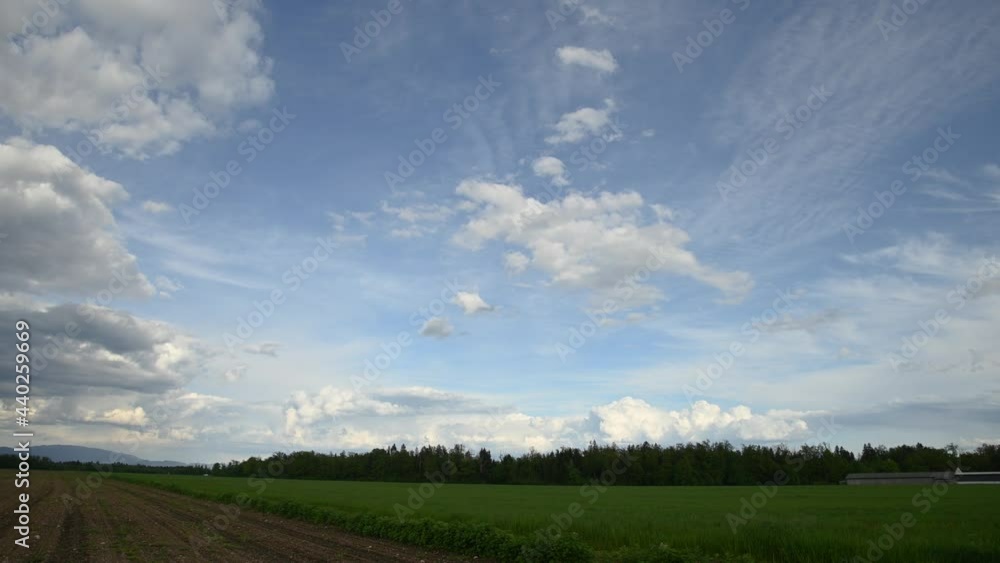 Time lapse of clouds moving fast over farmland farming field. Hot summer day. Agronomy and agriculture concept. Green and brown landscape against blue sky. Static shot, wide angle Time lapse of clouds moving fast over farmland farming field. Hot summer day. Agronomy and agriculture concept. Green and brown landscape against blue sky. Static shot, wide angle