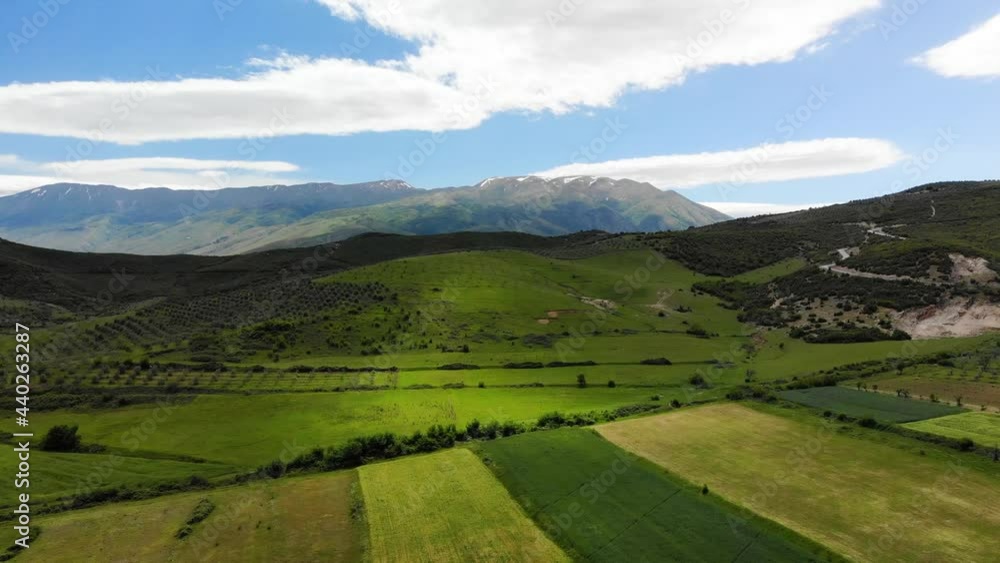 Aerial panoramic view of scenic landscape in the Alps with rugged alpine mountain peaks and lush blooming meadows on a sunny day with beautiful clouds and blue sky in summer. Albania Aerial panoramic view of scenic landscape in the Alps with rugged alpine mountain peaks and lush blooming meadows on a sunny day with beautiful clouds and blue sky in summer. Albania