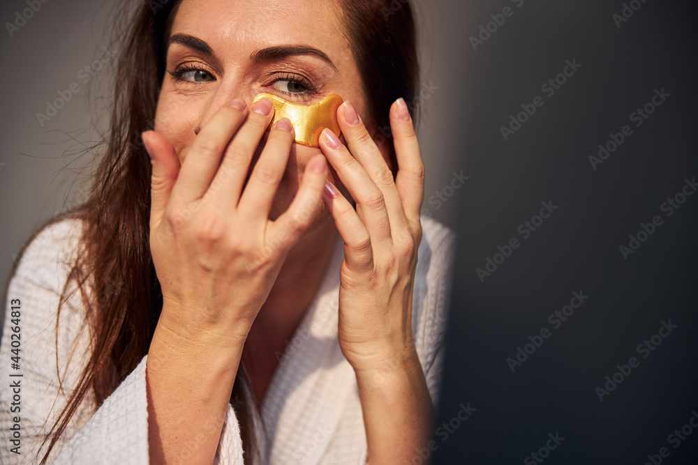 Attentive young female putting patches on face Attentive young female putting patches on face