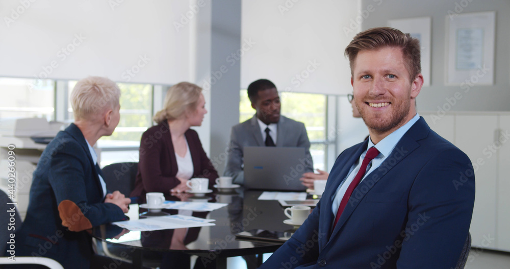 Handsome businessman at corporate meeting looking at camera and smiling Handsome businessman at corporate meeting looking at camera and smiling