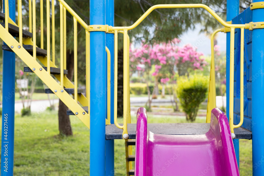 Yellow, purple and blue slide in the playground against the beautiful nature background Yellow, purple and blue slide in the playground against the beautiful nature background