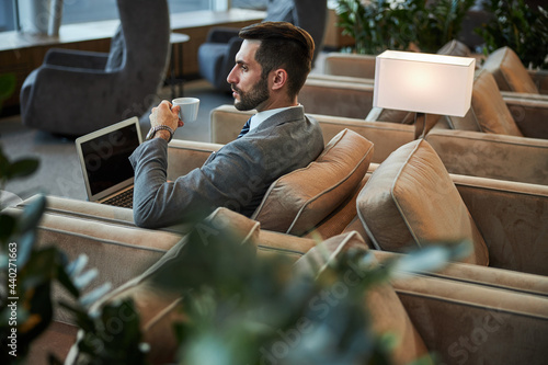 Serious handsome person drinking coffee in the business lounge