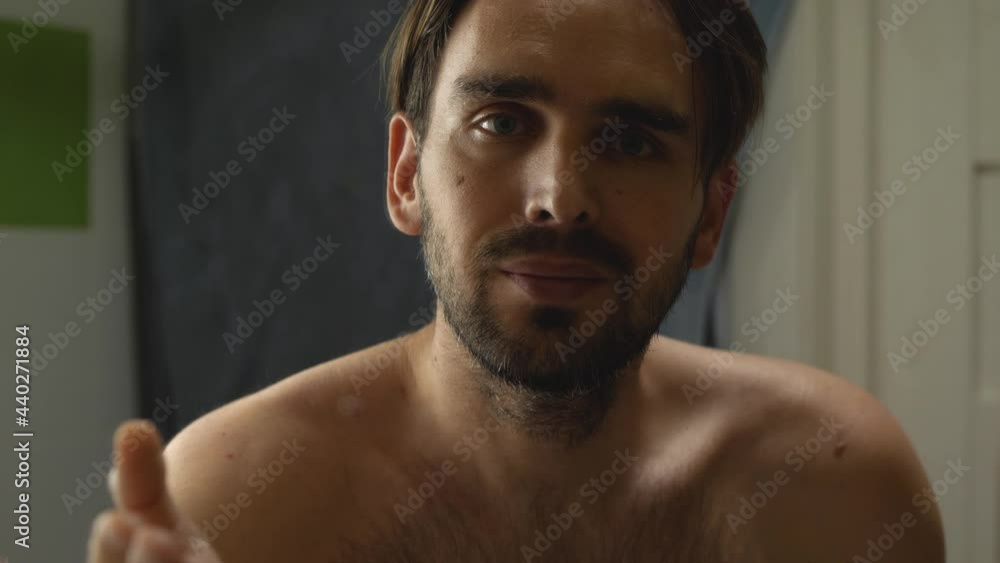 A man in the bathroom without a shirt looks at himself in the mirror. He kisses the palm of his hand and blows a kiss A man in the bathroom without a shirt looks at himself in the mirror. He kisses the palm of his hand and blows a kiss