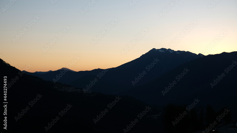 Silhouette of mountains against the background of a sunset or dawn sky. The sun went down behind the mountains. View of moody sunset in the mountains.