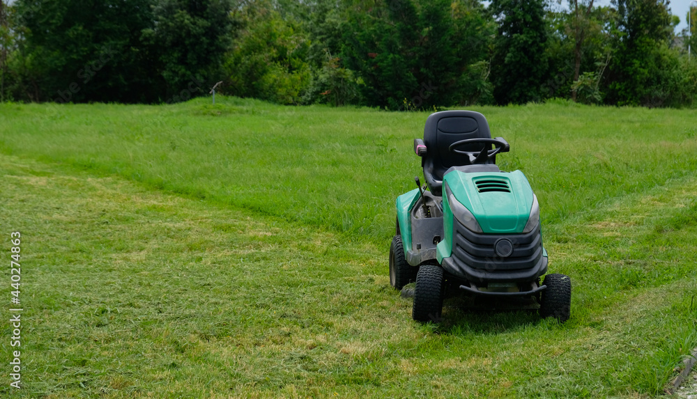 Foto de Green grass trimming with lawn mower. Tractor mowing grass in a