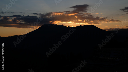 Silhouette of mountains against the background of a sunset or dawn sky. The sun went down behind the mountains. View of moody sunset in the mountains. © Yuliya