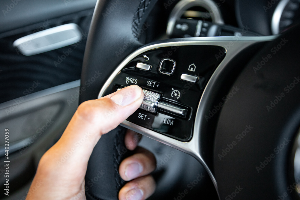the hand holding the buttons on the steering wheel of the car