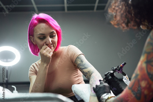 Female tattooist making tattoo on hand with machine in salon photo