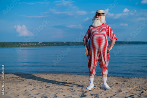 фотографія An elderly man in a striped retro swim suit and Boater on the seashore