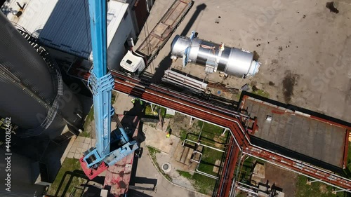 Wallpaper Mural Aerial view of a factory with large industrial tanks and equipment being moved by a crane, showcasing industrial operations and logistics from a drone perspective. Torontodigital.ca