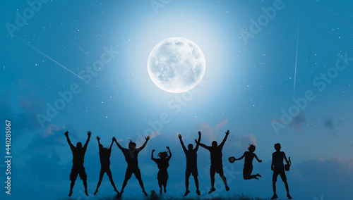 Silhouette of friends jumping at aurora with full blue moon "Elements of this image furnished by NASA "