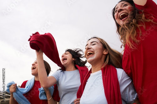 Fotografie Group of female supporters of a soccer team watching a game in the stands wearing blue t-shirts