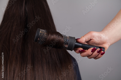 Professional Hairdresser female combing caucasian woman's hair.