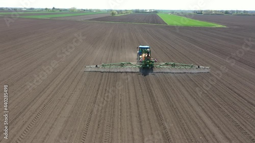 Aerial view of tractor spraying on field with sprayer, herbicide and pesticide