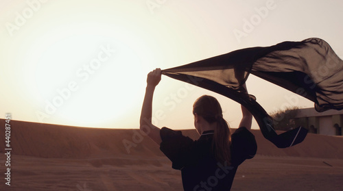 Portrait of a young Arab woman wearing traditional black clothing during beautiful sunset over the desert. photo