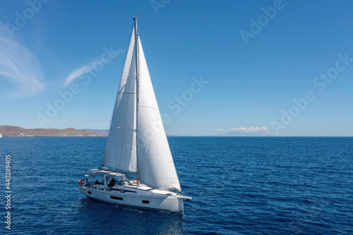 Sailing boat with open white sails, blue sky and rippled sea background © Rawf8