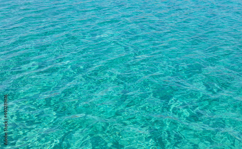 Sea surface turquoise blue color background, some reflections. Calm crystal clear water with small ripples. © Rawf8