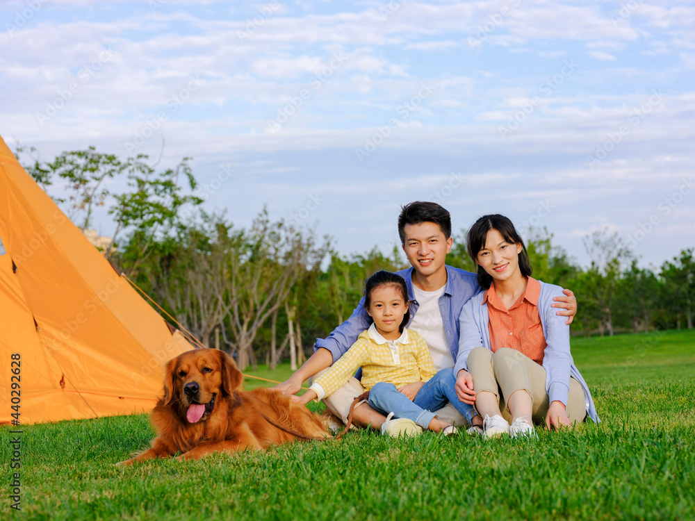 Fototapeta premium Happy family of three and pet dog in the park