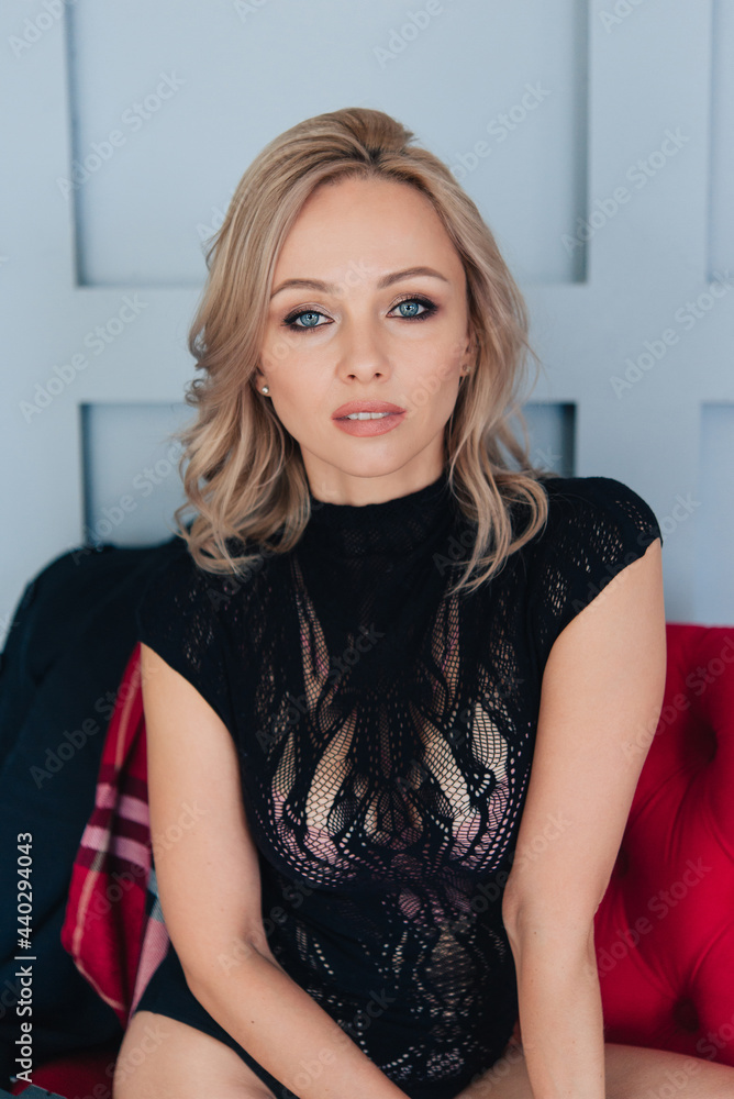 Beautiful blonde in a black bodysuit. Long bare legs. Is sitting. Indoor portrait in the interior. Beautiful blonde in a black bodysuit. Long bare legs. Is sitting. Indoor portrait in the interior.