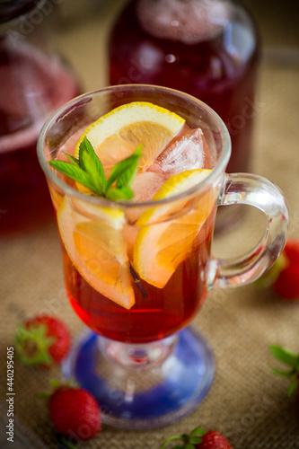 refreshing cool strawberry lemonade with lemon, ice and mint in a glass