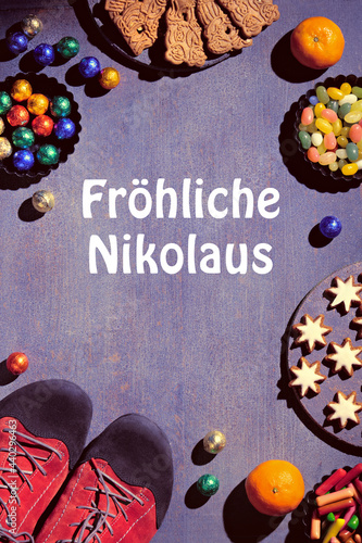 Text Frohliche Nikolaus means Happy St Nicolas Day. Traditional holiday in Germany and Western Europe on December 6. Various sweets, candy, cookies and pair of shoes on dark festive background.