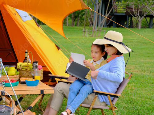 Happy mother and daughter sitting outside reading