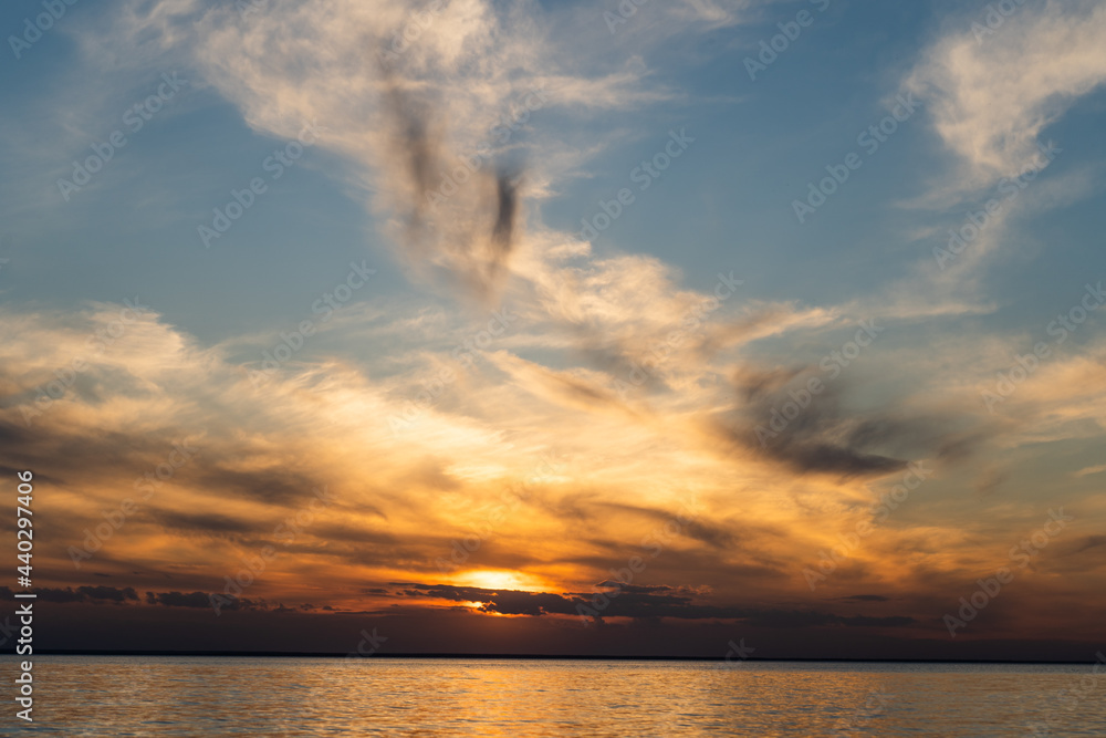 Sunset sky on the coast. Golden hour. Sky and clouds. Feather cloud. The sun went down below the horizon. Evening background