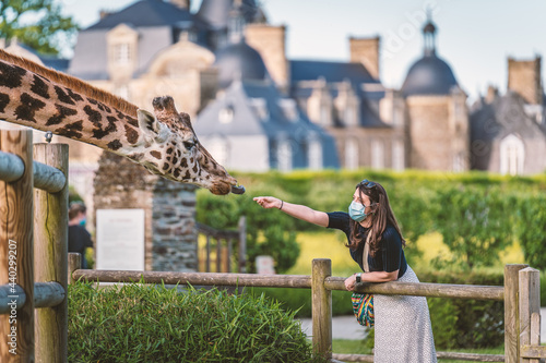 A young girl feeding a giraffe next to a castle