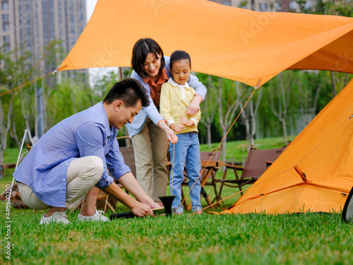 A happy family of three set up tents outdoors © eastfenceimage