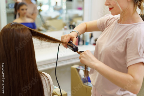 Beautiful young woman getting haircut by hairdresser in the beauty salon. Hair stylist in working process