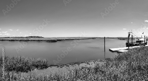 A black and white panoramic view of a tidal creek, shrimp boat, and salt-marsh on the Georgia coastline.