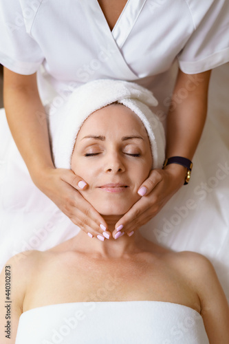 Face massage. Close-up of adult woman getting spa massage treatment at beauty spa salon. Spa skin and body care. Facial beauty treatment. Cosmetology. photo
