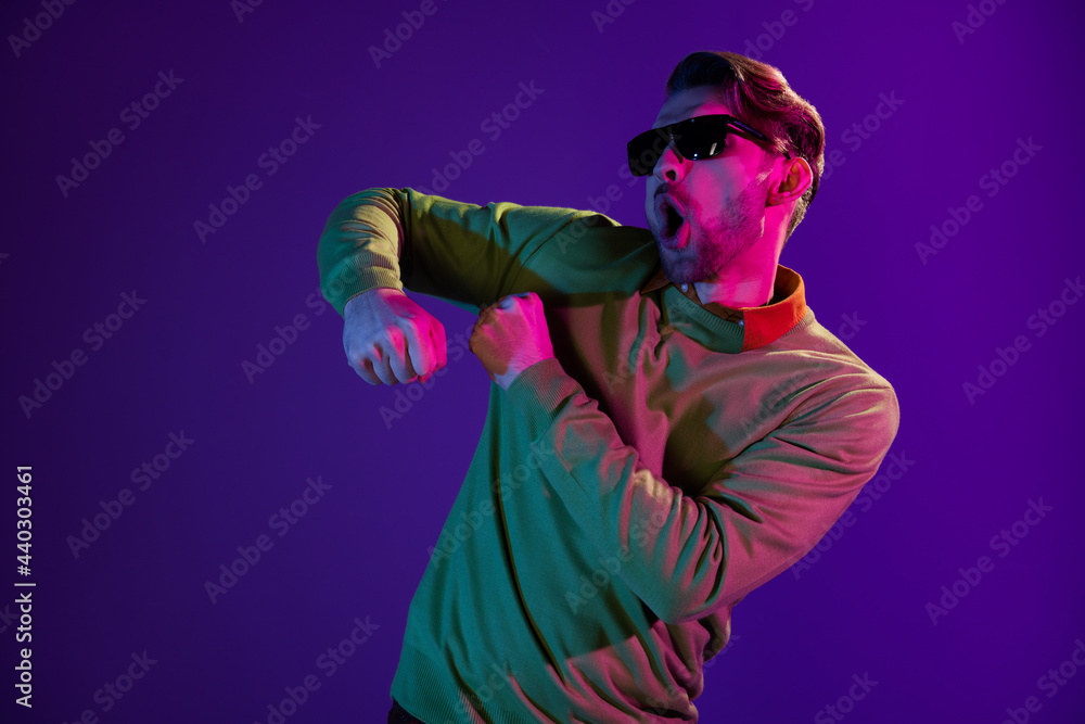 Photo of young excited man amazed shocked have fun carefree dance club nightlife isolated over neon color background Photo of young excited man amazed shocked have fun carefree dance club nightlife isolated over neon color background