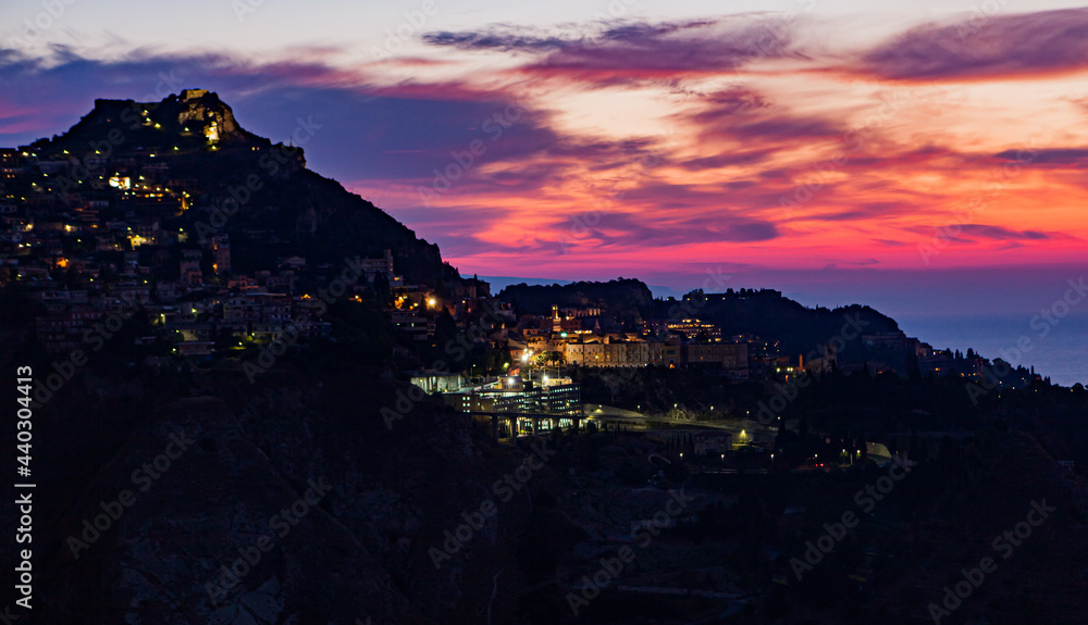 Colorful sunrise lights up the sky over Taormina, Sicily