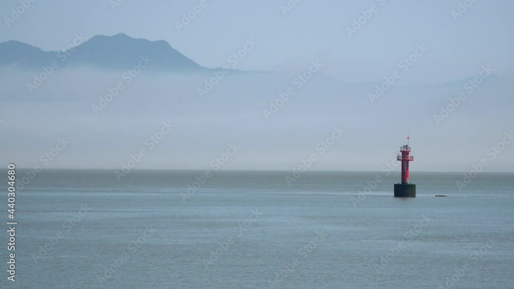 Navigational Buoy Floating in the Yellow Sea Between Islands, a Mountain Covered in dense white haze near Ganghwado island, South Korea close-up static Navigational Buoy Floating in the Yellow Sea Between Islands, a Mountain Covered in dense white haze near Ganghwado island, South Korea close-up static
