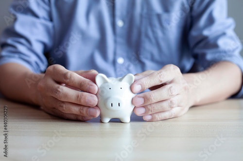 Businessman holding piggy bank on the wood table, business finance and saving money investment concept.