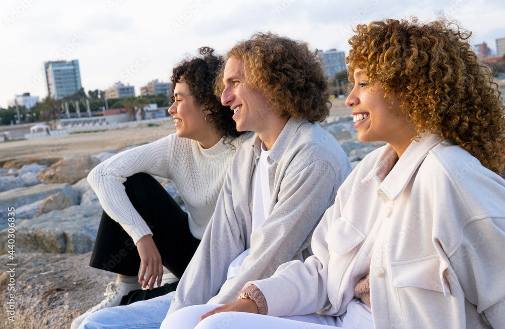 Close curly friends sitting on seafront