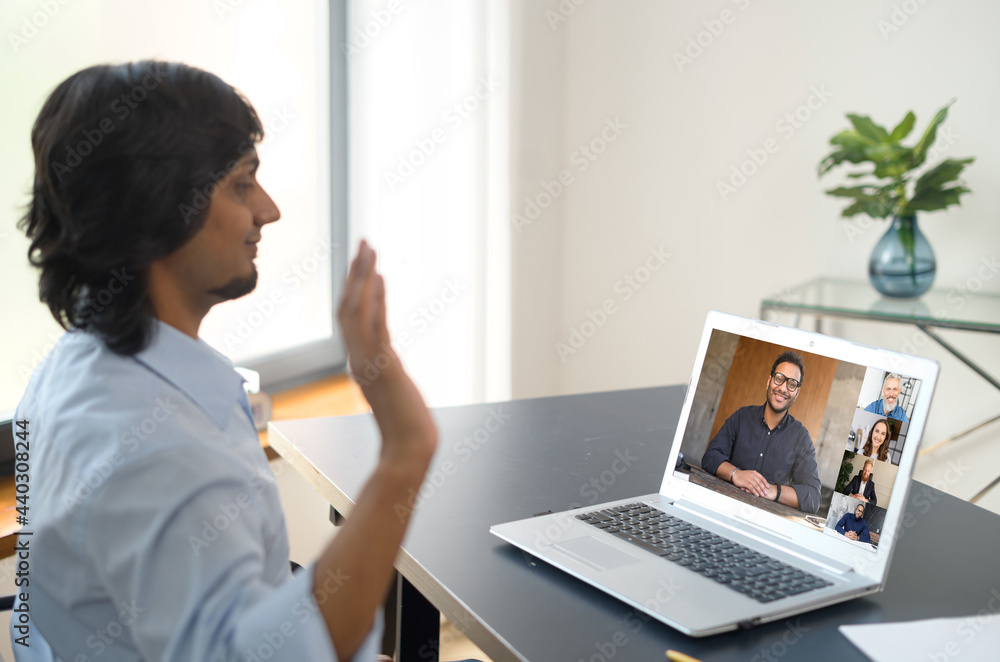 Indian man using computer application for distance video communication with coworkers, greeting webinar participants, meeting online, looking at the laptop screen with diverse people profiles Indian man using computer application for distance video communication with coworkers, greeting webinar participants, meeting online, looking at the laptop screen with diverse people profiles