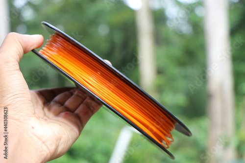 3D printing material made from bio plastic. PLA filament orange spool in hand.