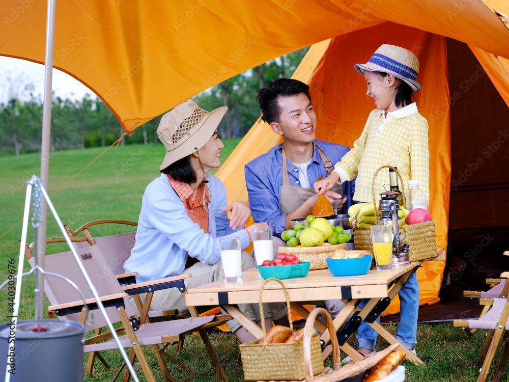 A happy family of three cooks outdoors A happy family of three cooks outdoors