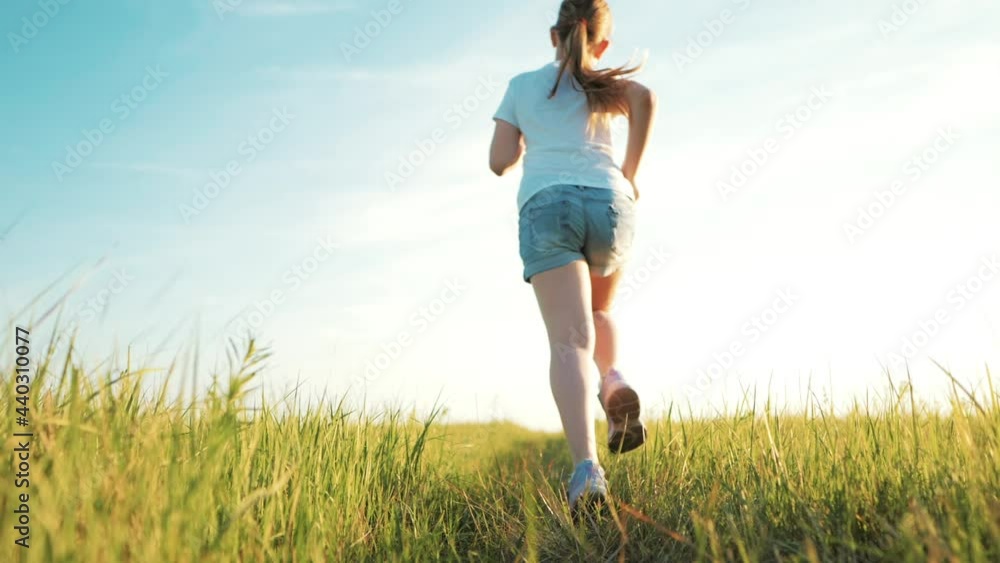 Happy childhood. Cheerful girl are running in the green meadow. Back view of girl running on flower meadow at evening twilight. Teen girl running on meadow with sunset. Happy family concept. Happy childhood. Cheerful girl are running in the green meadow. Back view of girl running on flower meadow at evening twilight. Teen girl running on meadow with sunset. Happy family concept.
