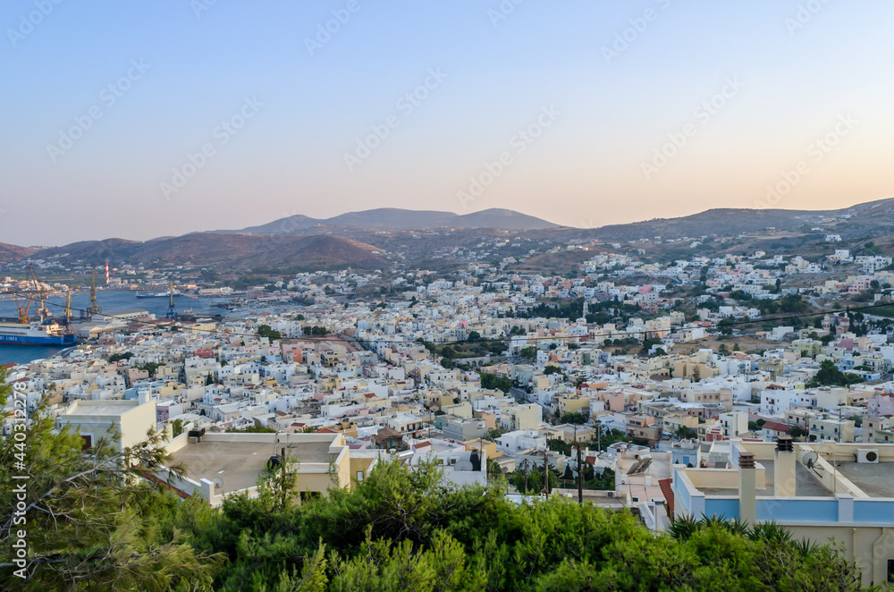 Panoramic View of Ermoupolis City, Syros Island, Greece from Above at Sunset. Beautiful Bay and View of the Aegean Sea, Mountains and Sky. Traditional White Houses, Villas and Port. 