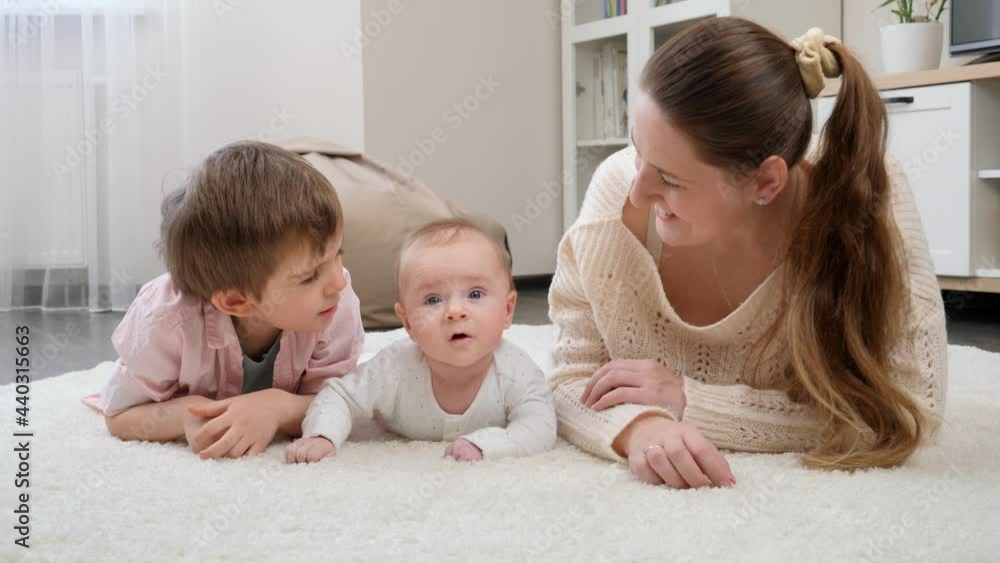 Cute little boys lying with young mother on carpet at living room. Parenting, children happiness and family relationship Cute little boys lying with young mother on carpet at living room. Parenting, children happiness and family relationship