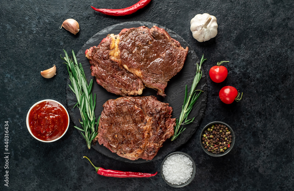 Two grilled ribeye steaks on stone background Two grilled ribeye steaks on stone background