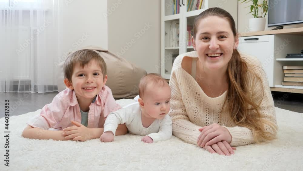 Happy smiling family lying on big carpet at living room and smiling in camera. Parenting, children happiness and family relationship Happy smiling family lying on big carpet at living room and smiling in camera. Parenting, children happiness and family relationship