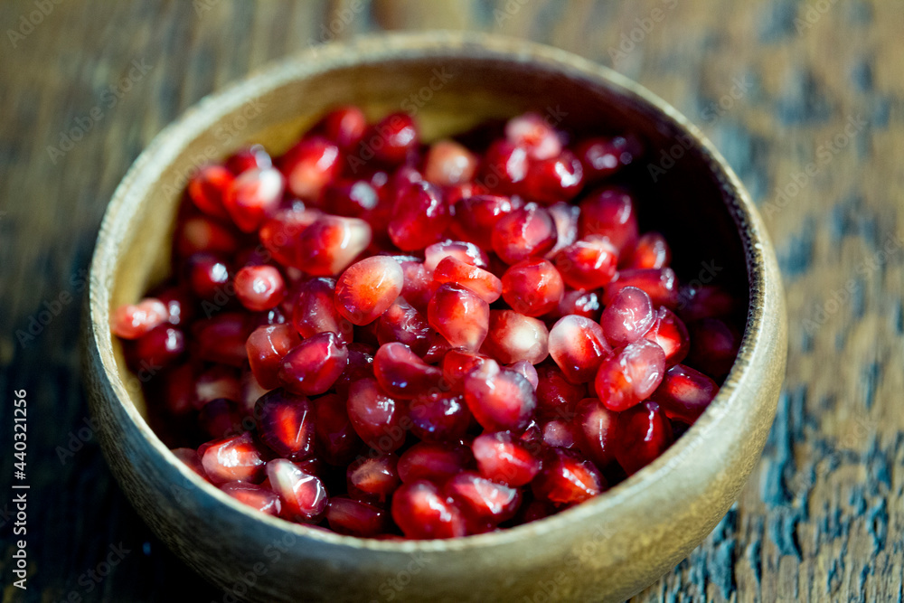 view of pomegranate seeds on a wooden bowl view of pomegranate seeds on a wooden bowl