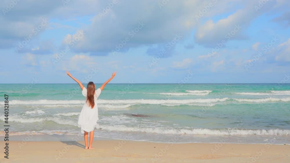 Slow-motion of Woman walking and jumping barefoot on the beach towards the sea in summer then she stops and raises hands up, Backside view handheld Slow-motion of Woman walking and jumping barefoot on the beach towards the sea in summer then she stops and raises hands up, Backside view handheld