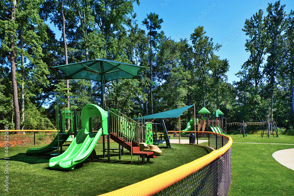 Green playground equipment including slides, awnings, monkey bars, stairs