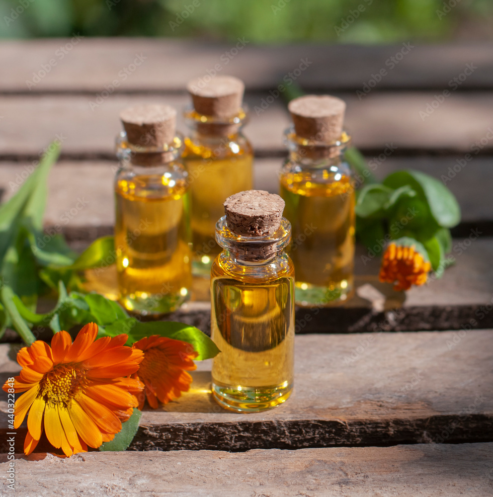 essential oil bottles with fresh calendula on the wood table essential oil bottles with fresh calendula on the wood table